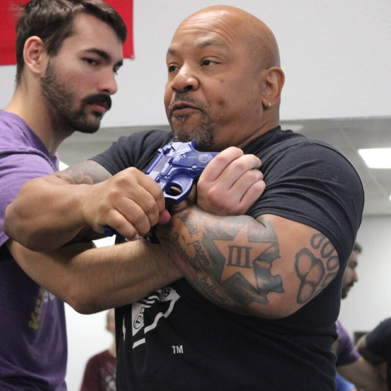Erik Hicks, owner and chief instructor at Krav Maga Dallas, demonstrating a gun defense technique with a student during training.